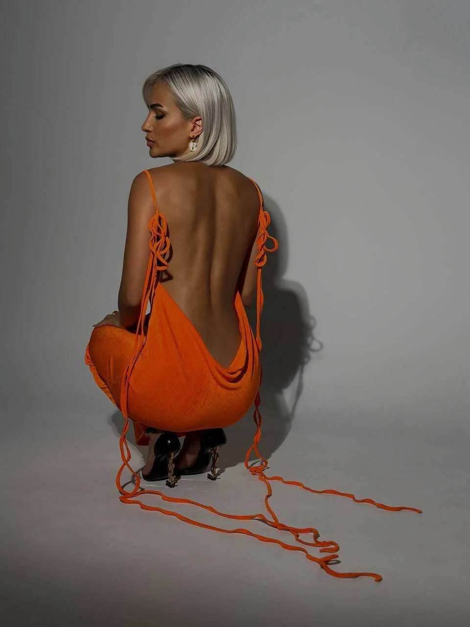 "Orange Karmen backless dress with adjustable ties, sleek modern design, perfect for casual outings or beach days."