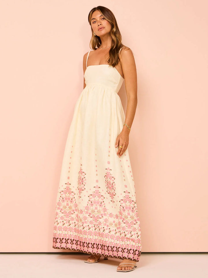 "White summer dress with intricate floral design on hem, perfect for sunny days outdoors."