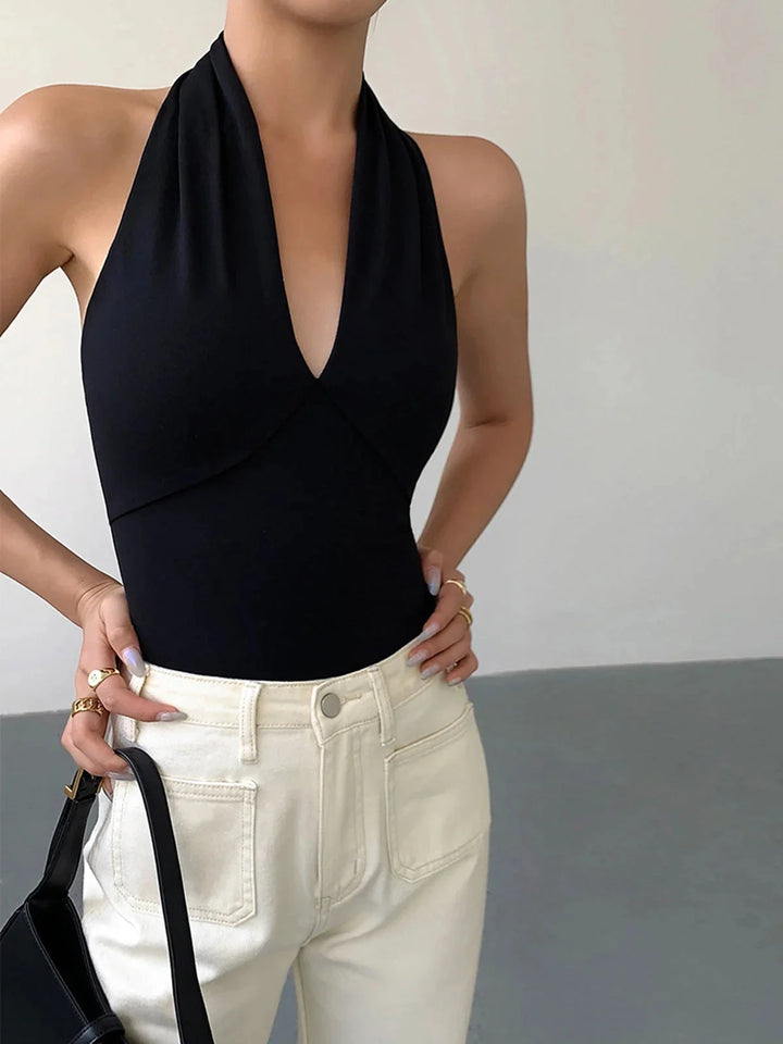 Black halter top with unique crossover design, made from sleek and comfortable material by Rhythm.