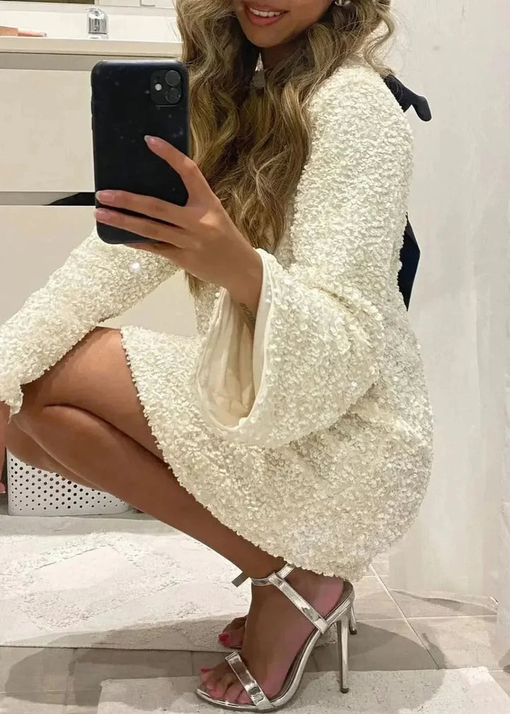 White mini dress featuring elegant neckline detail, sparkling fabric, and sleek design by Copelynn.