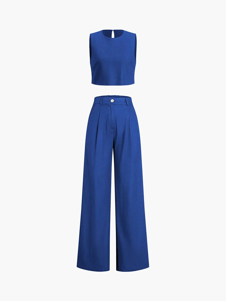 Black crop top with asymmetrical cut, paired with wide-leg pants in matching fabric and color. Feminine and chic ensemble…