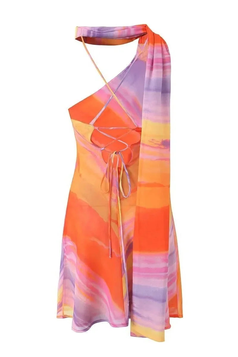 Alex Sunset tones halter mini dress featuring a vibrant pattern in warm colors with a halter neckline and mini length…