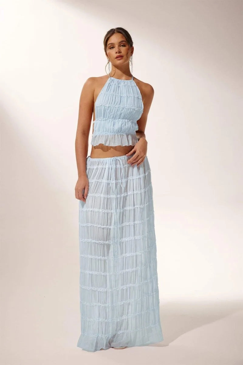 Light blue pleated halter crop top and skirt set made of airy fabric with a stylish design perfect for a chic summer look.