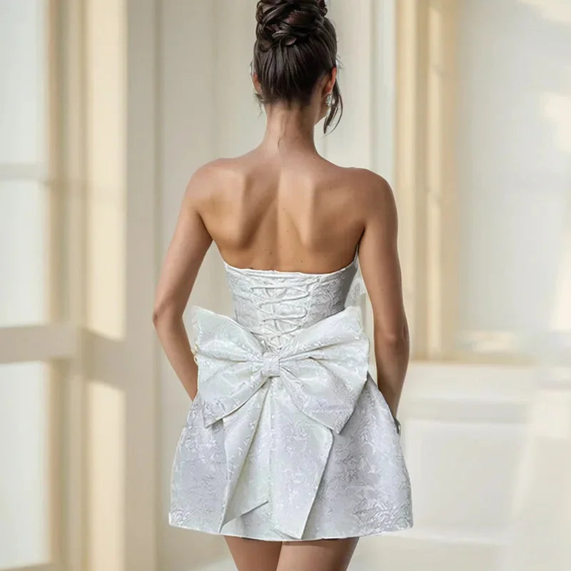 "Strapless mini dress in Zoey pink with oversized bow detail, perfect for summer occasions."