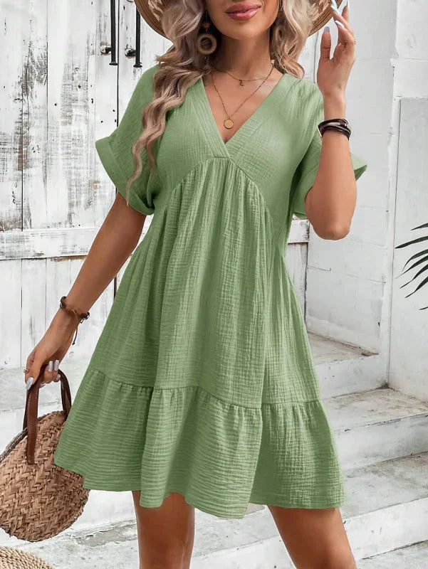 Green Rosabelle dress with ruffled layers, made of flowy and lightweight fabric, features a flattering v-neck design.
