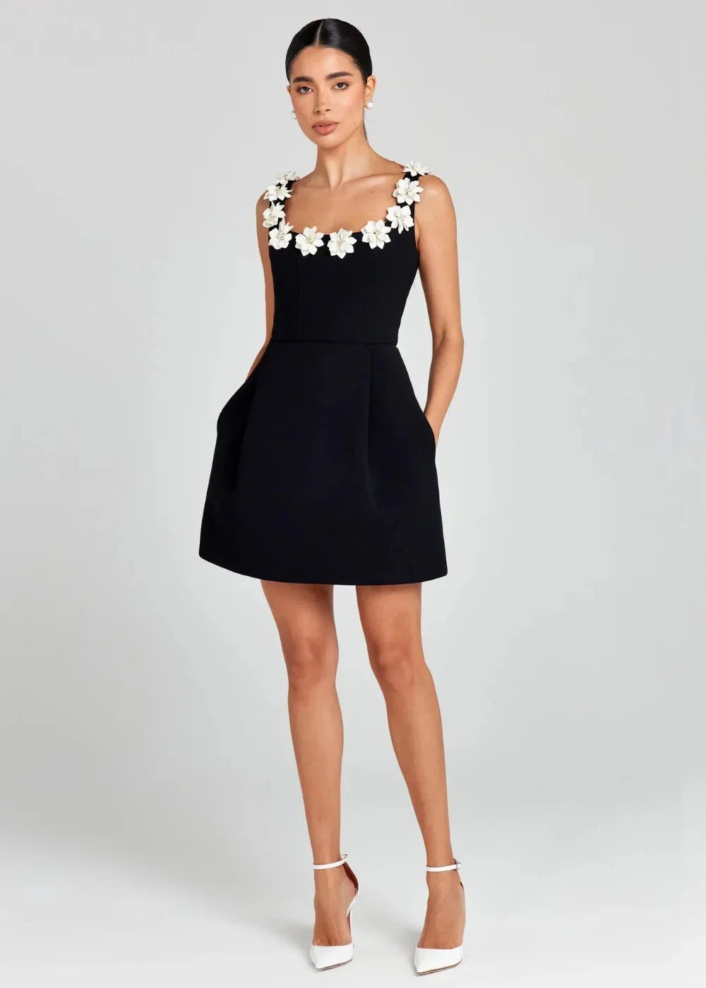 "Black mini dress with white floral embroidery detail, made of lightweight fabric, perfect for a chic and stylish look."