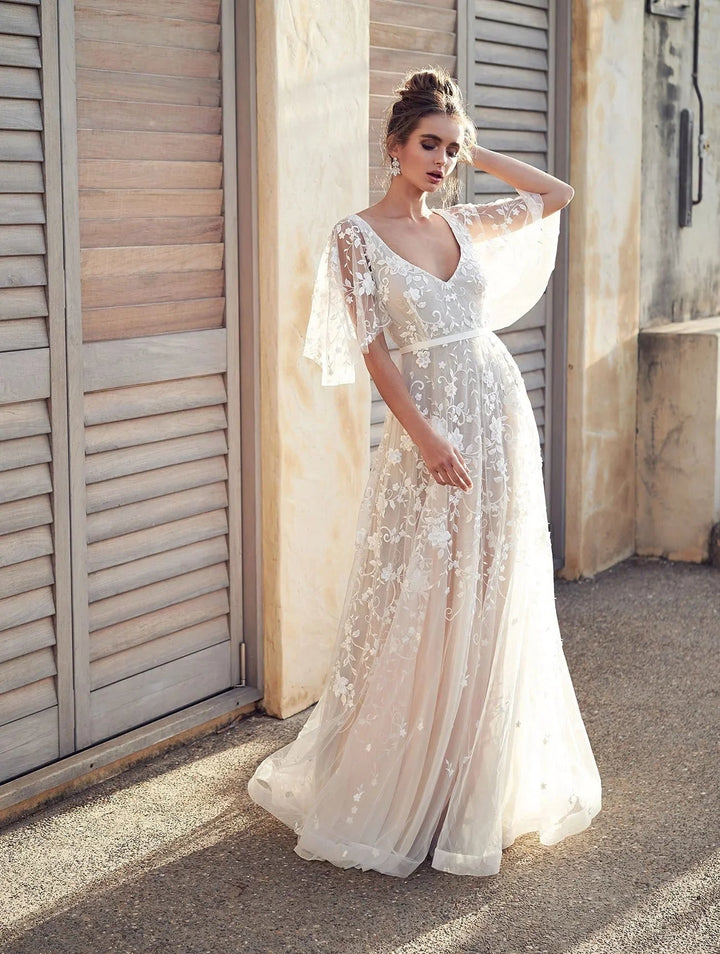 "White embroidered maxi dress with flutter sleeves, elegant design in airy fabric for a chic summer look by Lyric."
