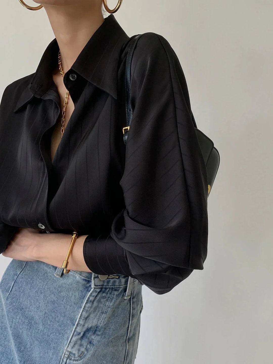 "Alaura black button-up shirt with elegant gold accents, made of sleek material, perfect for a sophisticated look."