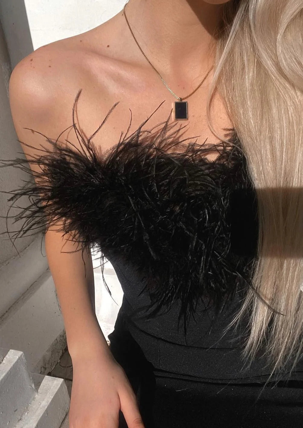 Black strapless dress with delicate feather trim, perfect for special occasions.