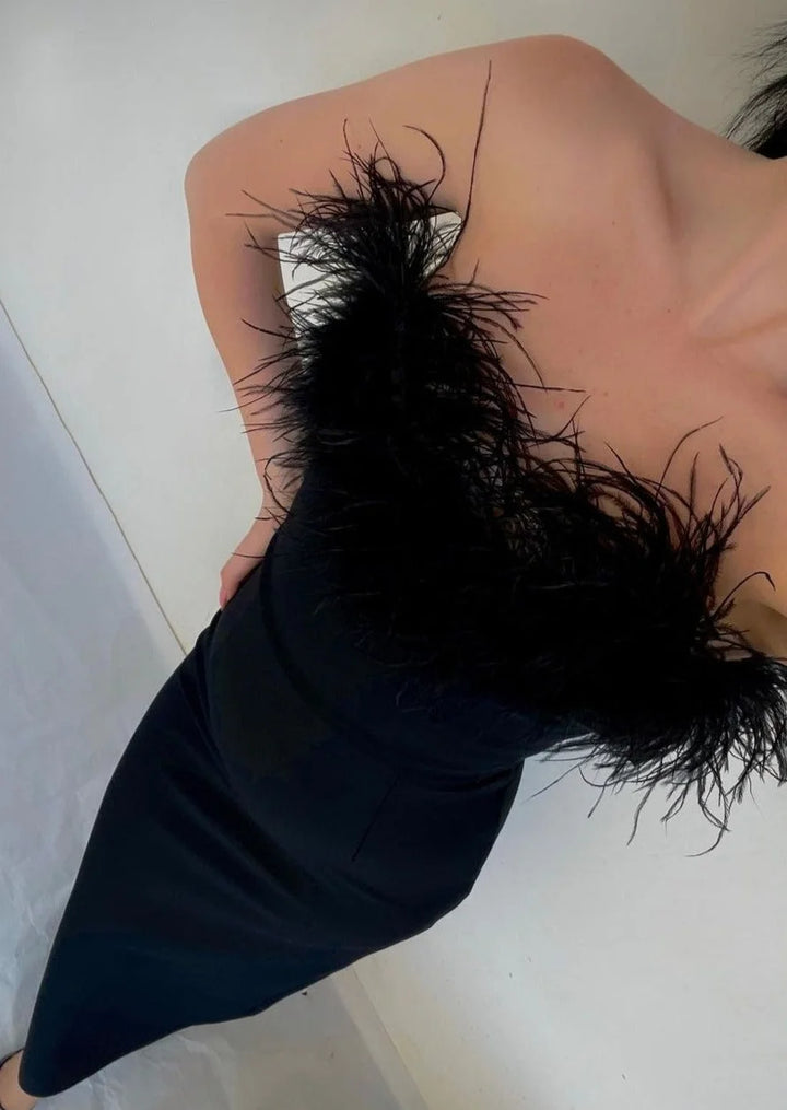 "Black strapless dress with feather trim, perfect for elegant occasions with a soft fabric, feather embellishments, and…