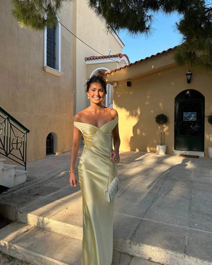 Cream off-shoulder maxi dress in Poppi fabric with matching clutch, perfect for a stylish and elegant look at any event.