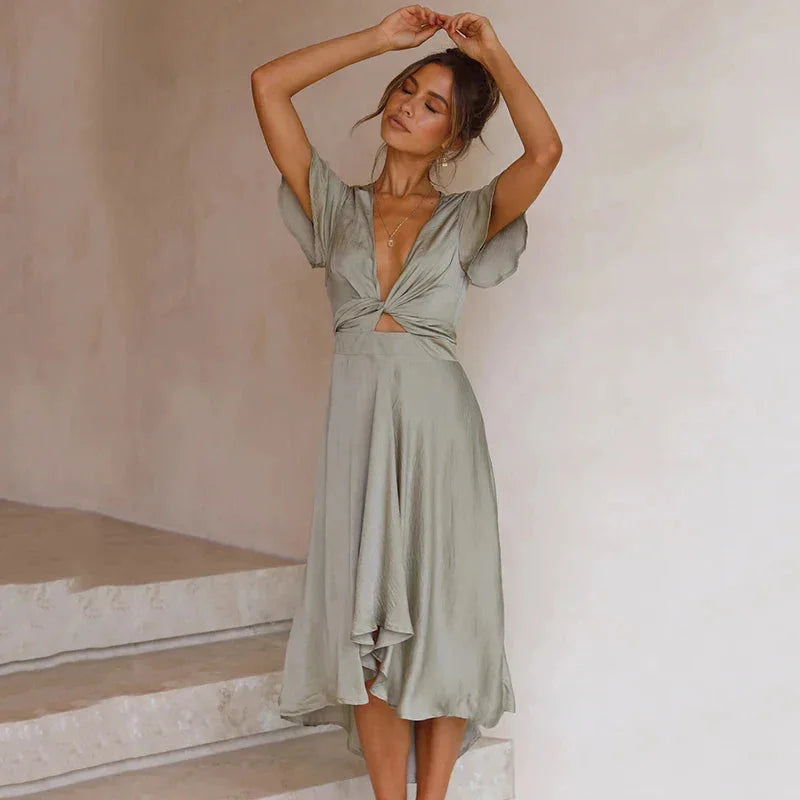 Green Adela midi dress with flutter sleeves, asymmetrical hem, and a flattering silhouette. Made from flowy and lightweight…