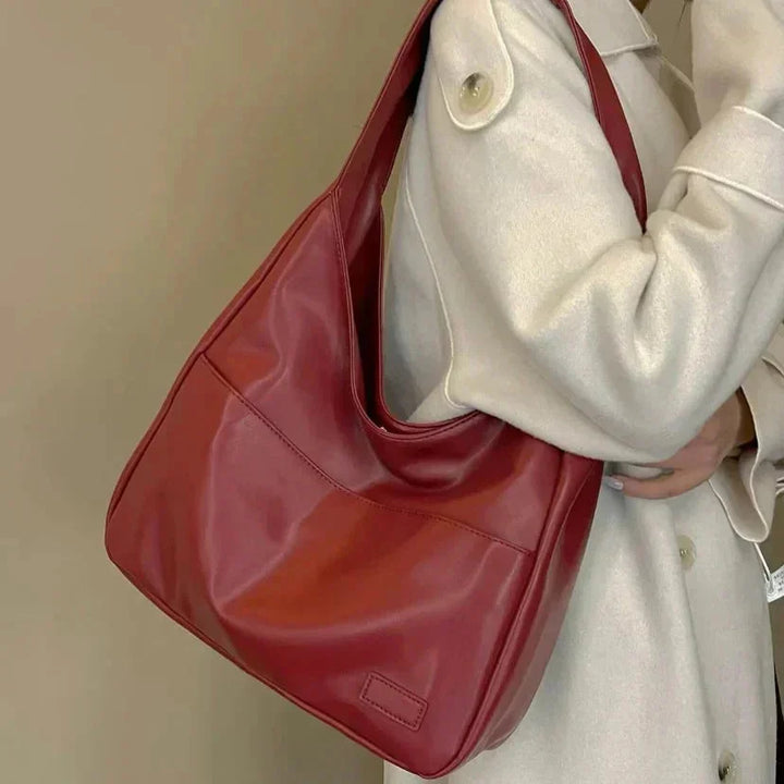 Black faux leather shoulder bag with a sleek minimalist design, featuring a structured shape and adjustable strap by Candy.