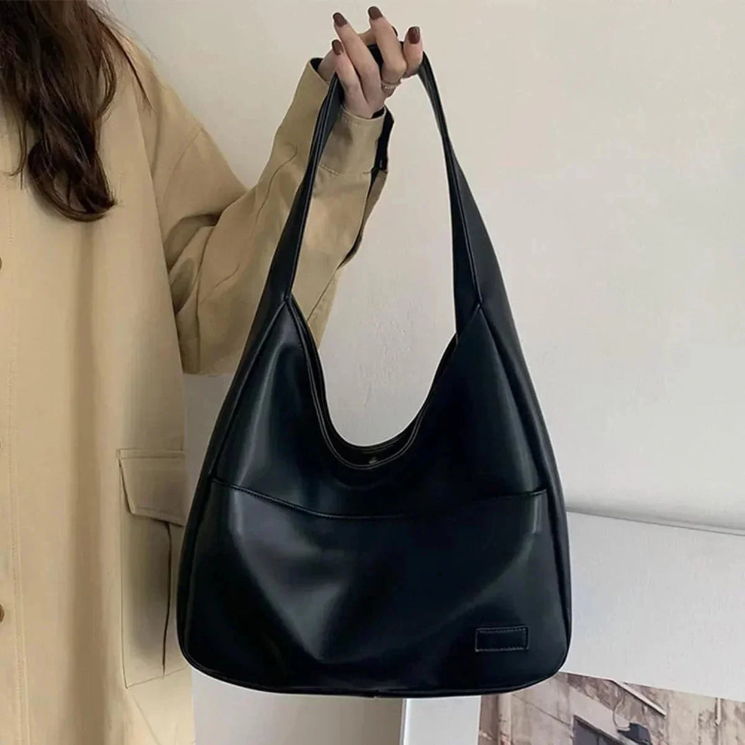 Black leather shoulder bag with clean lines and a minimalist design. Features a sleek modern aesthetic, perfect for everyday…