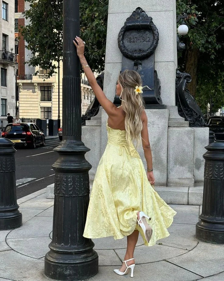 Yellow halter dress with pleated skirt, perfect for summer days. Made of soft, flowy fabric with a flattering silhouette.